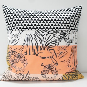 Puede incluir: Una almohada decorativa con un patrón geométrico blanco y negro en la parte superior, un fondo blanco con rayas de tigre negras en el medio y un fondo melocotón con rayas de tigre negras en la parte inferior.
