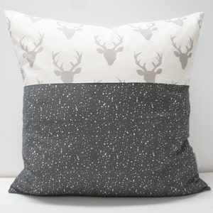 May include: A grey and white throw pillow with a deer print on one side and a grey speckled pattern on the other side.