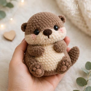 May include: A handmade crochet otter, approximately 15 cm tall, in shades of brown and cream. The otter has black eyes, a brown nose, and pink cheeks. The plush toy is a cute, cuddly animal.