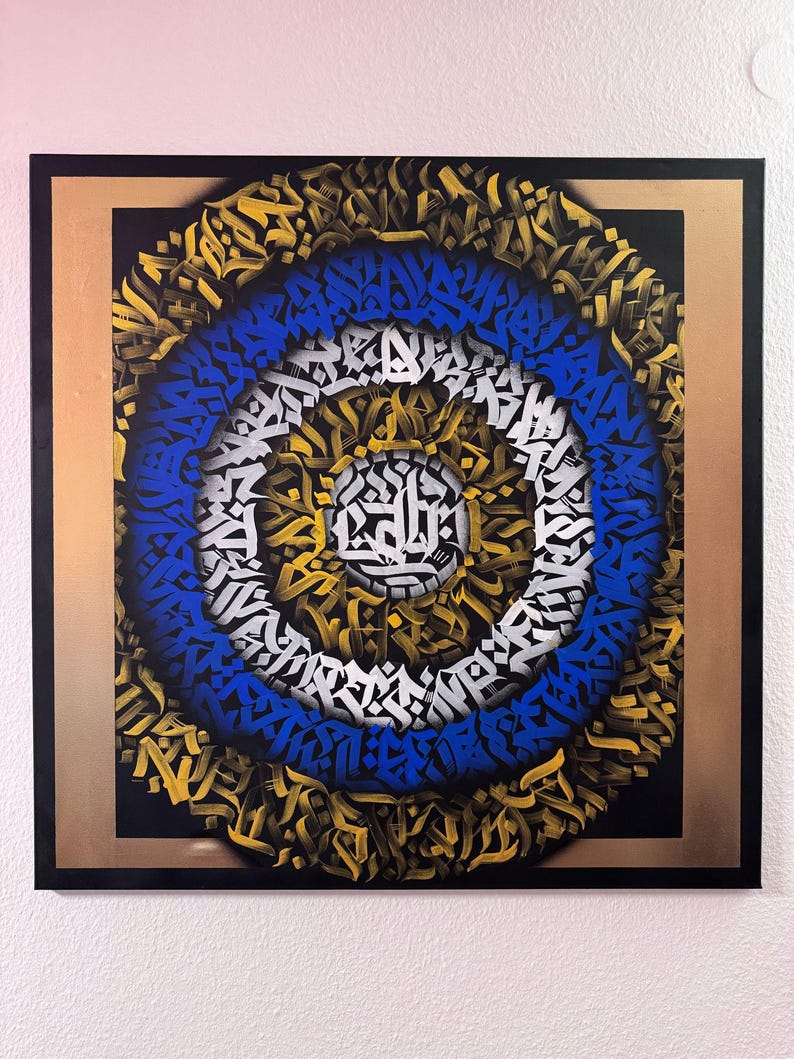 May include: A circular abstract painting with concentric rings of blue, white, and gold graffiti-style lettering on a black background. The painting is framed in a gold and black frame.