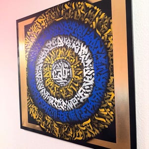 May include: A framed artwork featuring a circular design with concentric rings of blue, white, and gold abstract patterns. The artwork is set against a black background with a gold frame.