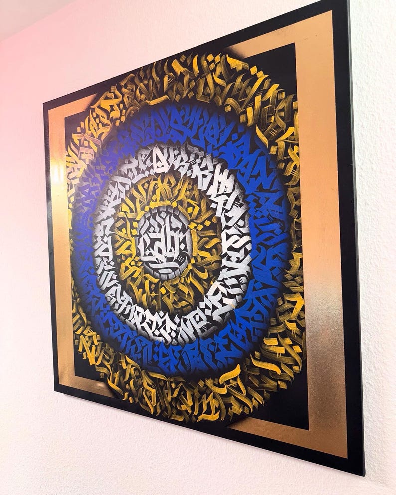 May include: A framed artwork featuring a circular design with concentric rings of blue, white, and gold abstract patterns. The artwork is set against a black background with a gold frame.