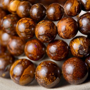 Peut inclure: Gros plan sur une collection de perles rondes en bois. Les perles sont de différentes nuances de marron, avec des motifs et des textures uniques. Les perles semblent être enfilées, peut-être pour un bracelet ou un collier.