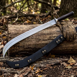 May include: A curved steel blade with a dark wooden handle and a silver bolster. The blade features a central fuller groove. A black leather sheath with brass-colored rivets and a tan leather work glove are positioned alongside the blade.