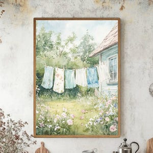 May include: A watercolor painting depicting a clothesline with hanging laundry in a garden. The scene features a light blue house, green trees, and a field of pink and white flowers. The laundry includes various shirts and linens in blue and white.
