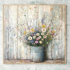 May include: A square canvas painting depicting a bouquet of colourful wildflowers in a weathered light blue metal bucket. The flowers include white daisies, yellow blossoms, and purple petals. The background features vertical light wood planks.