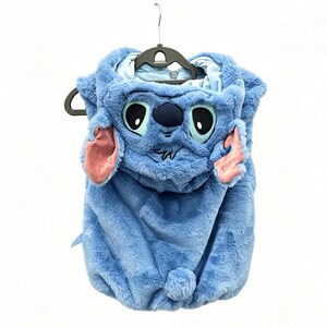 May include: A blue plush costume resembling the character Stitch from the animated film Lilo & Stitch. The costume features a hood with Stitch's face, including large eyes, a dark blue nose, and pink ears. The costume is hanging on a black hanger.