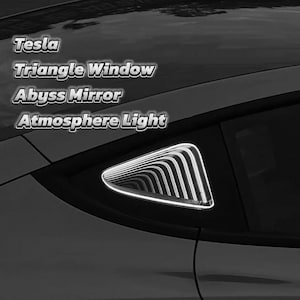 Puede incluir: Un coche Tesla con una ventana triangular que tiene una tira de luz blanca. El texto "Tesla Triangle Window Abyss Mirror Atmosphere Light" es visible sobre la ventana.
