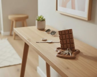 May include: A brown, rectangular, grid-patterned chocolate bar-shaped key holder with a matching base tray. The tray holds a set of silver-toned metal keys. The object is made of a solid, matte material and features a molded, blocky design.