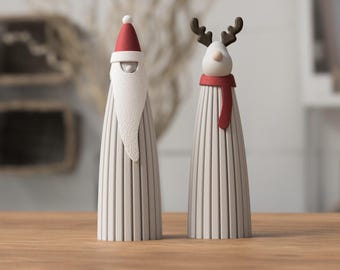 May include: Two cone-shaped figurines with vertical ribbed textures. One figure wears a red hat with a white pom-pom and a long white beard. The other figure features brown antlers and a red scarf wrapped around its neck.