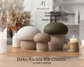 Può includere: Tre oggetti decorativi a forma di fungo con cappelli lisci e arrotondati in bianco, beige e verde oliva, dotati di basi cilindriche a coste. Il testo sull'immagine include AS DEKO PRODUCTION, In verschiedenen Farben erhältlich, Einzeln oder als Set, e Deko Kürbis Rib Classic SCANDI / JAPANDI.