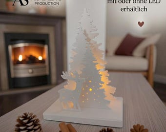 May include: A white wooden decorative ornament featuring a layered pine tree silhouette and a standing deer figure on a rectangular base. The design includes small star-shaped cutouts and is illuminated from within by a warm light.