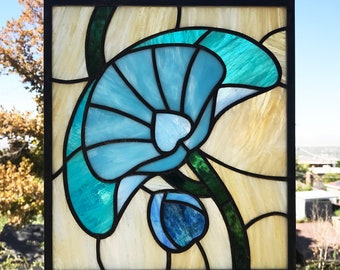 May include: A stained glass window panel featuring a blue and green flower with a yellow background.