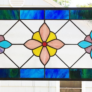 May include: A stained glass window with three floral designs. The designs are in shades of pink, blue, yellow, and red. The window is framed in black.