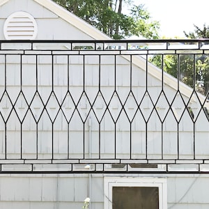 May include: A large, rectangular stained glass window with a diamond pattern. The window is made of clear glass and black metal framing.