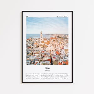 Può includere: Una stampa incorniciata con una vista aerea di Bari, Italia, che mostra una chiesa bianca con un alto campanile in mezzo a un paesaggio urbano di tetti rossi. Il cielo è azzurro e la stampa include il nome e le coordinate della città.