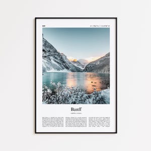 May include: A framed print featuring a scenic view of Banff, Alberta, Canada. The image showcases a snow-covered mountain range reflected in a turquoise lake. The text "Banff" and descriptive text are at the bottom.