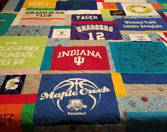 May include: A patchwork quilt made from t-shirts with various logos and text, including "Carroll", "Grand Slam Club", "Yager", "Chargers 12", "Indiana", "Maple Creek Basketball", "Winners Train Losers Complain", and "Coming together is a beginning. Staying together is progress. Working together is success."