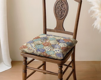 May include: A wooden chair with a high back featuring an oval carved detail and a square seat cushion. The cushion displays a repeating pattern of interlocking quatrefoil shapes in shades of blue, red, and cream with intricate floral motifs.