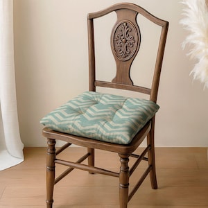 May include: A wooden chair with a decorative back and a seat cushion. The cushion has a light blue and white chevron pattern. The chair is made of wood and has a classic design.