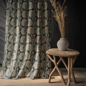 Könnte beinhalten: Dunkelblauer Vorhang mit Blumenmuster und passendem Blumendesign. Ein kleiner, runder, gewebter Beistelltisch mit einer grauen Keramikvase mit getrockneten Pflanzen befindet sich neben dem Vorhang. Der Vorhang hat ein sich wiederholendes Muster aus Blumen und Blättern.