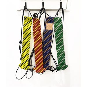 May include: Four drawstring backpacks with striped designs in yellow and black, red and gold, blue and gold, and green and silver. The backpacks are hanging against a white background.