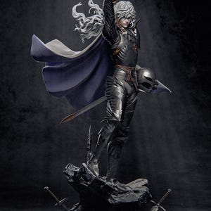 May include: A detailed statue of a character in dark armour, holding a sword aloft. The figure has long, flowing white hair and a cape. A helmet is held in the other hand. The statue stands on a rocky base with swords at the base.