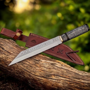 May include: A silver blade knife with a dark wood handle and a brown leather sheath. The blade has etched runes and decorative lines. The sheath is brown with a leather strap and stitching.