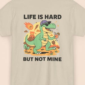 Das Leben ist hart, aber nicht meins – Dinosaurier-T-Shirt – Lustiges Cartoon-T-Shirt | Unisex-Baumwollshirt | Entspannte Dino-Vibes | Kostenloser Versand