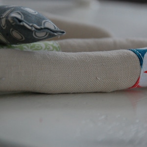 Może przedstawiać: Rurka z beżowego materiału z kolorowym geometrycznym wzorem na jednym końcu. Wz&oacute;r przedstawia białą gwiazdę z czerwonymi, pomarańczowymi, ż&oacute;łtymi, zielonymi i niebieskimi akcentami.