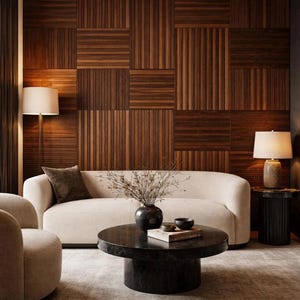 May include: A living room featuring a wall with dark brown wood paneling in a grid pattern, a cream-colored curved sofa, a round black marble coffee table, a matching armchair, two floor and table lamps, and a textured light gray area rug.