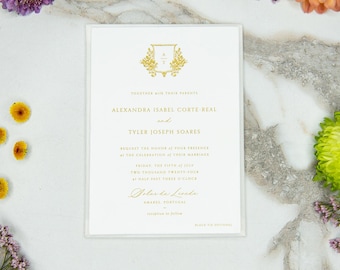 Könnte beinhalten: Eine formelle Hochzeitseinladung mit goldfarbenen Buchstaben und einem dekorativen Wappen. Die Einladung enthält die Namen des Paares, das Datum und den Ort der Zeremonie. Die Einladung ist von Blumen umgeben.