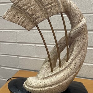 May include: A ceramic table lamp with a white and brown abstract design. The lamp has a black base and gold metal accents.