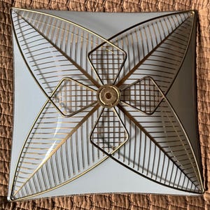 May include: Square, vintage ceiling light fixture with a white background and gold-colored metal leaf and geometric designs. The fixture has a central circular element and is likely from the mid-century era.
