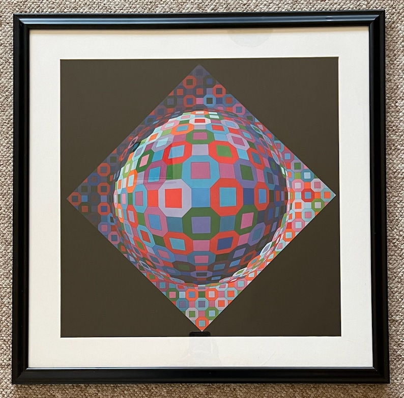 Puede incluir: Una impresi&oacute;n enmarcada de un dise&ntilde;o geom&eacute;trico abstracto colorido. El dise&ntilde;o presenta una esfera compuesta por cuadrados y rect&aacute;ngulos en tonos de rojo, azul, verde y morado. La esfera se coloca sobre un fondo marr&oacute;n oscuro.