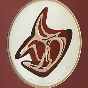 May include: An abstract artwork titled "Overload" by Susan Kohl, featuring a layered design in shades of red, brown, and beige. The artwork is set within a gold-toned oval frame against a maroon background. The edition number 10/36 is visible.