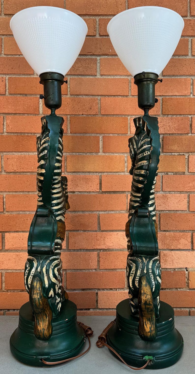 K&ouml;nnte beinhalten: Paar Vintage-Tischlampen in Gr&uuml;n mit wei&szlig;en, strukturierten Glasschirmen. Die Lampen haben ein geschnitztes Design mit goldenen Akzenten. Jede Lampe ist etwa 76 cm hoch.