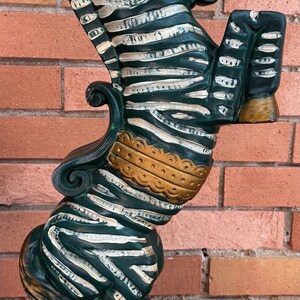 K&ouml;nnte beinhalten: Vintage Seepferdchen-Lampe mit dunkelgr&uuml;nem Sockel und K&ouml;rper, wei&szlig;en Streifen und goldenen Akzenten. Die Lampe hat die Form eines Seepferdchens mit einem zebraartigen Muster und einem roten Auge.