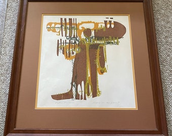 May include: A framed abstract print in brown, green, and yellow tones. The print features a stylized figure with geometric shapes and lines. The title "Stepping In The Moonlight" is printed below the image.