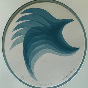 May include: A blue and white abstract art print of a bird in flight. The print is titled "Soaring" and is signed by the artist "Susan Kohl" with the year "76".