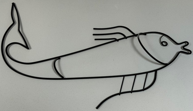 May include: Black metal fish wall decor with a stylized design. The fish has a curved body and a rounded head with a simple eye.