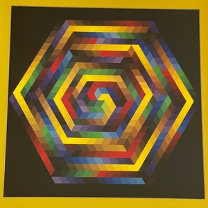 May include: A framed abstract geometric art print. The artwork features a colorful, multi-layered hexagonal design with a spiral center. The color palette includes yellow, red, blue, green, and brown hues against a black background.