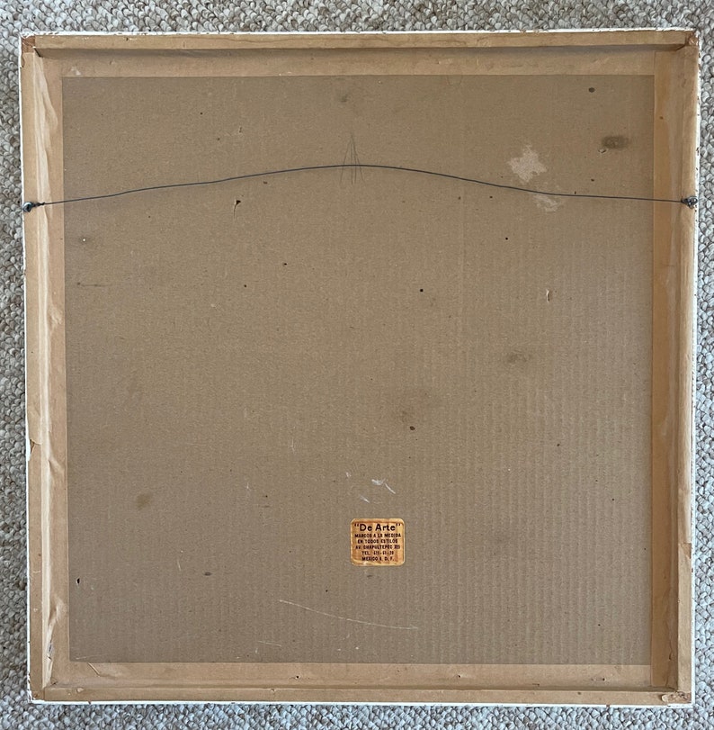 May include: Back of a framed artwork with a white wooden frame. The artwork backing is cardboard with a wire for hanging. A small sticker in the lower right corner reads "De Arte".