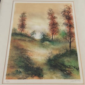 May include: A framed print of a watercolor painting depicting a landscape with trees in shades of green, brown, and red. The sky is a soft yellow with a hint of orange. The print is numbered 85/100.