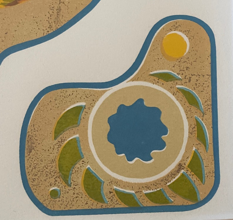 May include: A tan and brown ceramic tile with a blue and green design. The tile has a circular design with a blue center and green leaves around it. There is a yellow circle in the upper right corner of the tile.