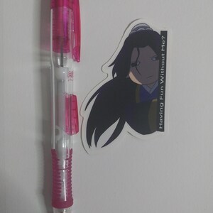 May include: A clear and pink mechanical pencil with a pink grip and accents, next to a sticker featuring a cartoon character with long black hair and the text "Having Fun Without Me?"