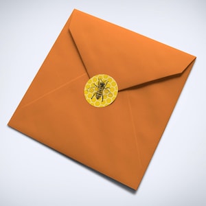 May include: An orange envelope with a round sticker featuring a bee on a honeycomb pattern.