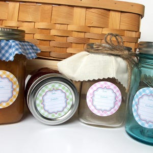 May include: Four glass jars with labels featuring a gingham pattern and the text "Date & Contents". The jars are filled with different coloured liquids and are arranged in a row on a wooden surface.