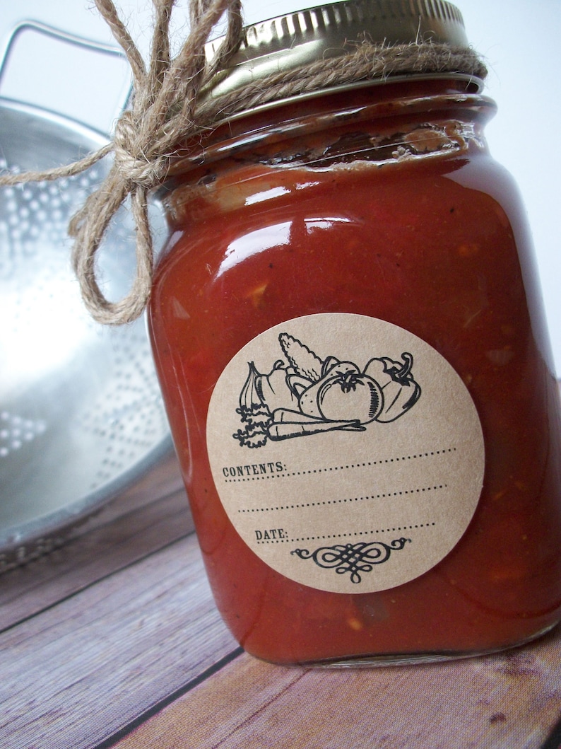 May include: A glass jar with a red sauce inside. The jar has a brown paper label with a black and white illustration of vegetables and the text "CONTENTS: DATE:".