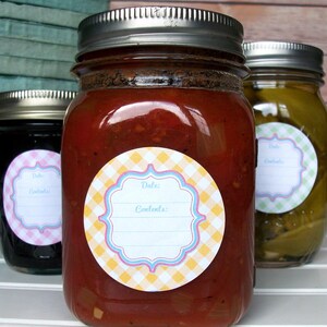 May include: Three glass jars with silver lids and labels. The labels are round and have a yellow and white checked pattern with a blue and pink border. The labels have the words "Date:" and "Contents:" printed on them. The jars are filled with different coloured liquids.